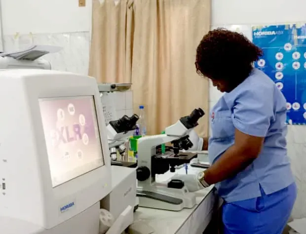 Technicienne de laboratoire au microscope à la Clinique COGEMO.